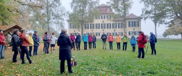 Pilgergruppe steht auf einer Wiese vor einem großen Gebäude